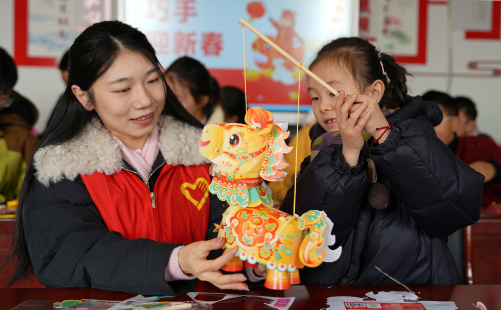 2026年2月12日,在江苏省海安市墩头镇新时代文明实践站,志愿者陪同当地留守儿童一起做新年饰品。新华社发(周强摄)