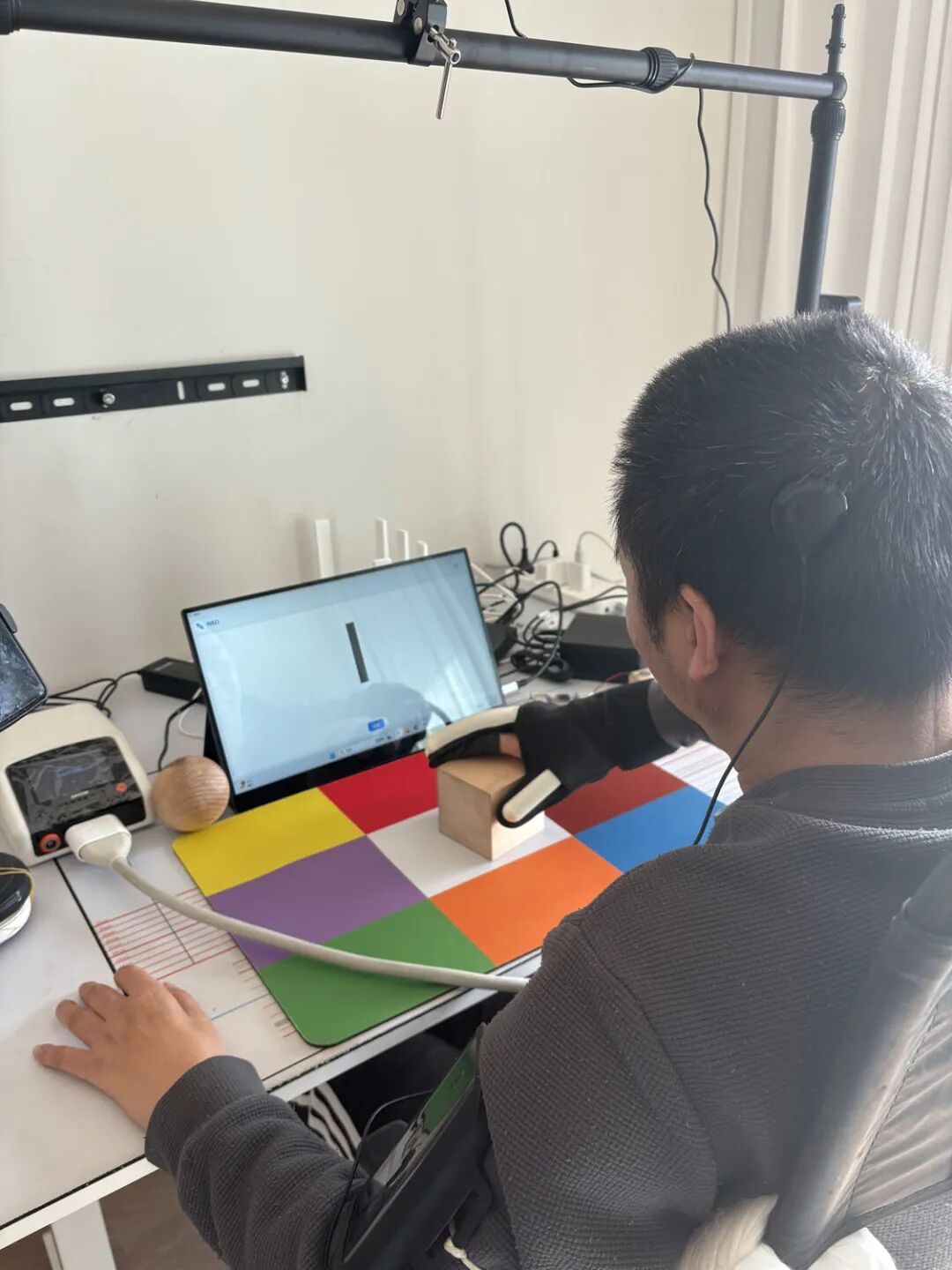 2025年11月,董辉在上海进行脑机接口训练,正在用气动手套抓握木块 / 南风窗记者 朱秋雨 摄