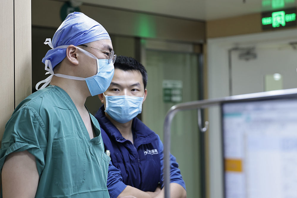 2月4日2时许，一位外科医生（左）和重症监护病房医生交接一名刚刚做完手术病人的病情。