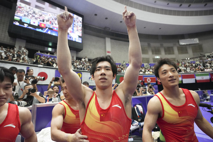 2026年9月23日,中国队选手张博恒(中)和田昊(右)庆祝夺冠。在爱知·名古屋亚运会体操项目男子团体决赛中,中国队夺得冠军。新华社发(吕小炜摄)