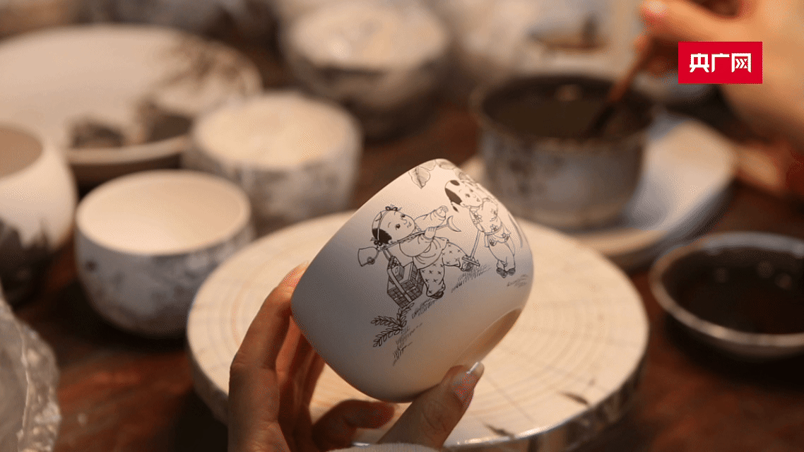 景德镇青花人物制作技艺非遗传承人吴帆在瓷坯上描绘纹饰(央广网记者 周蓓 制作)