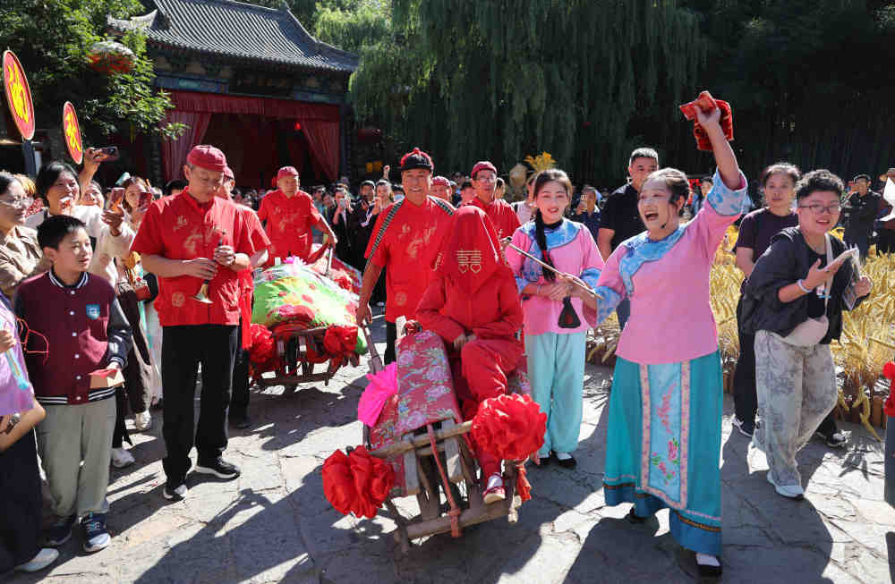 10月5日,在山东省临沂市沂南县竹泉村,游客在观看《沂蒙婚嫁》表演。新华社发(王彦冰 摄)