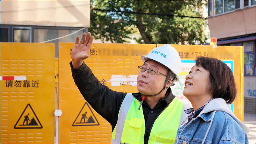 工作人员为居民讲解电梯安装细节。人民网 李成伟摄