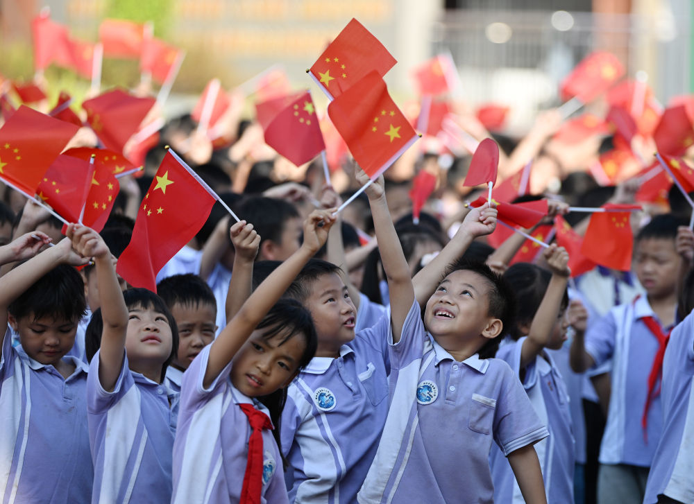 9月30日，小学生在广西梧州市苍海第二小学迎国庆主题活动中挥舞国旗。新华社记者 黄孝邦 摄