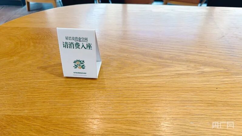 店内桌子上摆放的“请消费入座”提示牌(央广网记者 朱冠安 摄)