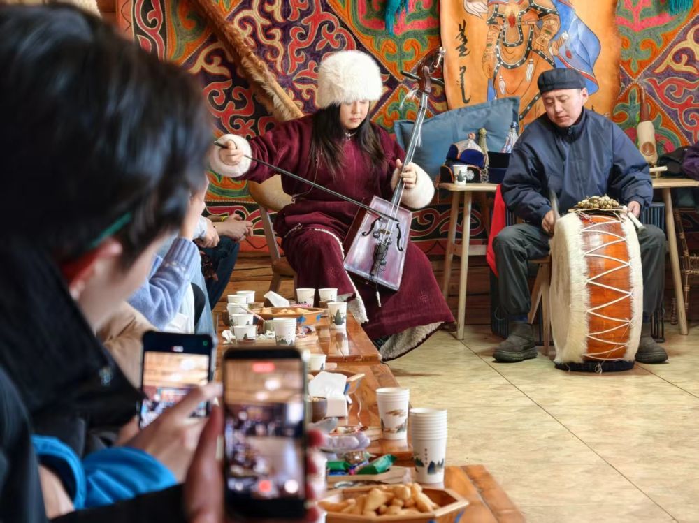 1月30日,台湾青年在新疆喀纳斯景区欣赏蒙古族图瓦人演奏。新华社记者 贺小童 摄