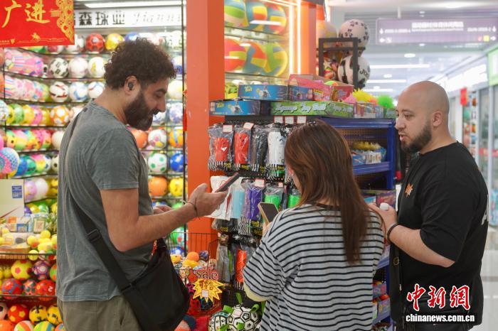 外籍采购商在义乌一店铺前咨询商品。董易鑫 摄