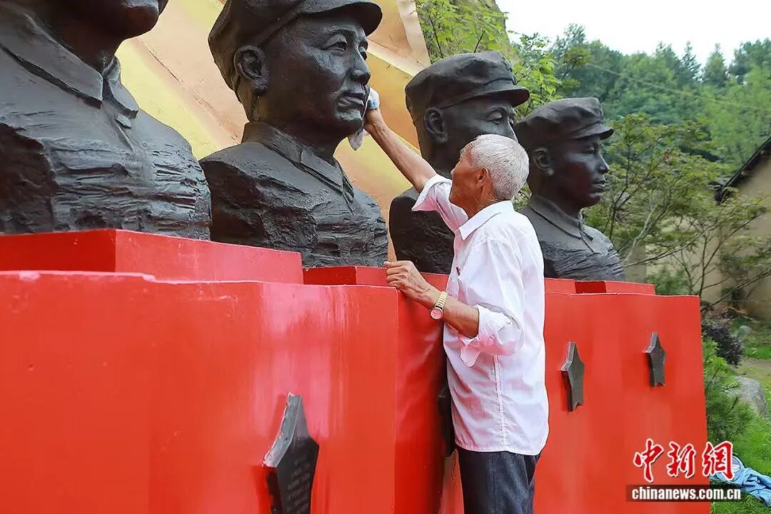 图为王茂贵老人清理烈士塑像。光山县委宣传部供图