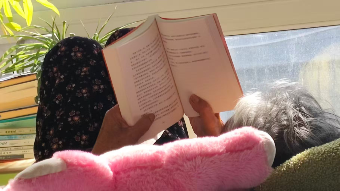 茸茸的姥姥柳树梅在家中翻阅《脐带纪事》实体书。(图/受访者供图)