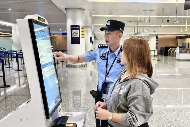 7月13日，在重庆江北国际机场，重庆出入境边防检查总站民警帮助泰国旅客填写入境信息。新华社发（曾言延 摄）