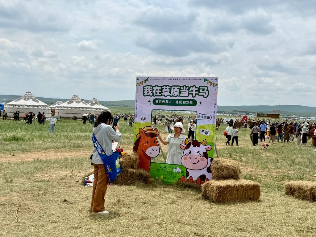 游客在那达慕大会会场与特色标语合影打卡。新华社记者 陈玉麒 摄