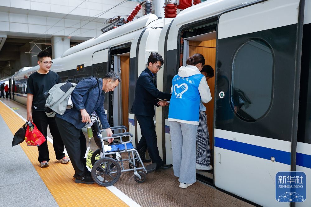 ↑ 5月15日，铁路工作人员和志愿者为特殊旅客乘车提供帮助。新华社发（宋佳龙摄）