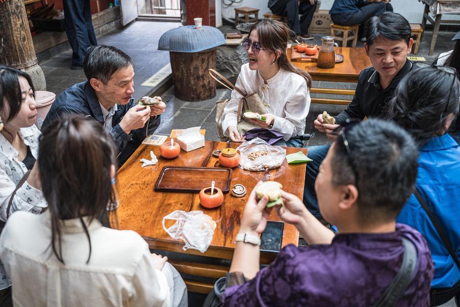 10月19日,游客在腾冲市清水镇三家村中寨司莫拉佤族村品尝大米粑粑。