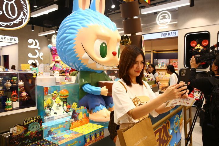 2024年7月5日，在泰国曼谷的泡泡玛特店内，一名女子在拉布布玩偶前自拍。新华社记者 孙玮彤 摄