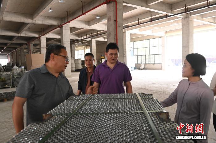 3月24日,庄钛德(左三)与叔叔庄文祈(左一)向来客介绍工厂生产情况。中新社记者 蒋雪林 摄
