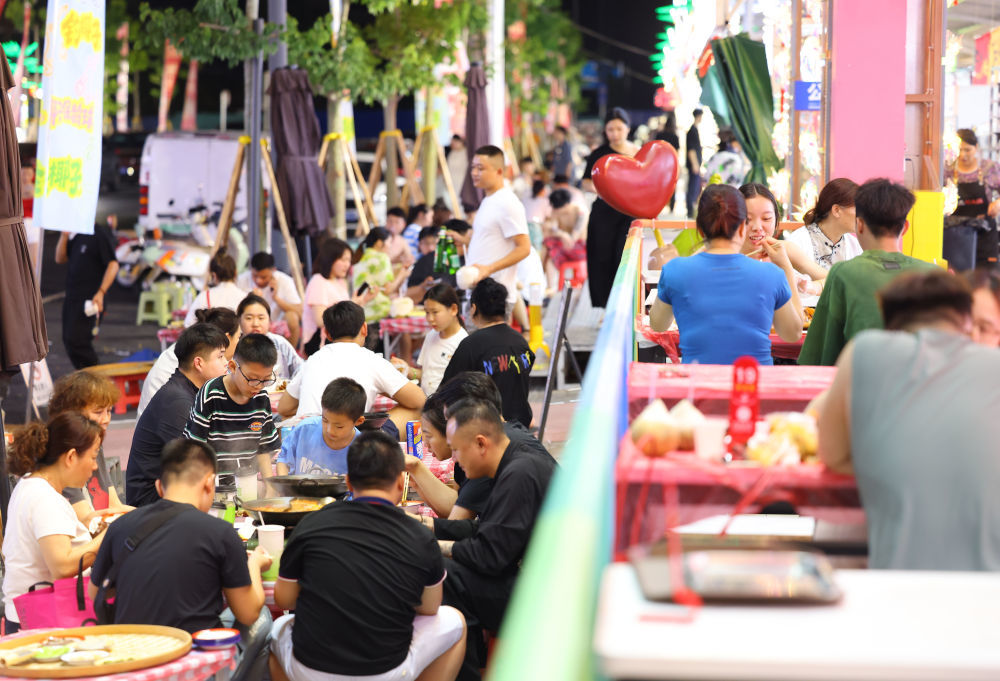 5月3日,人们在海南省三亚市街头一夜市品尝美食。新华社发(陈文武摄)