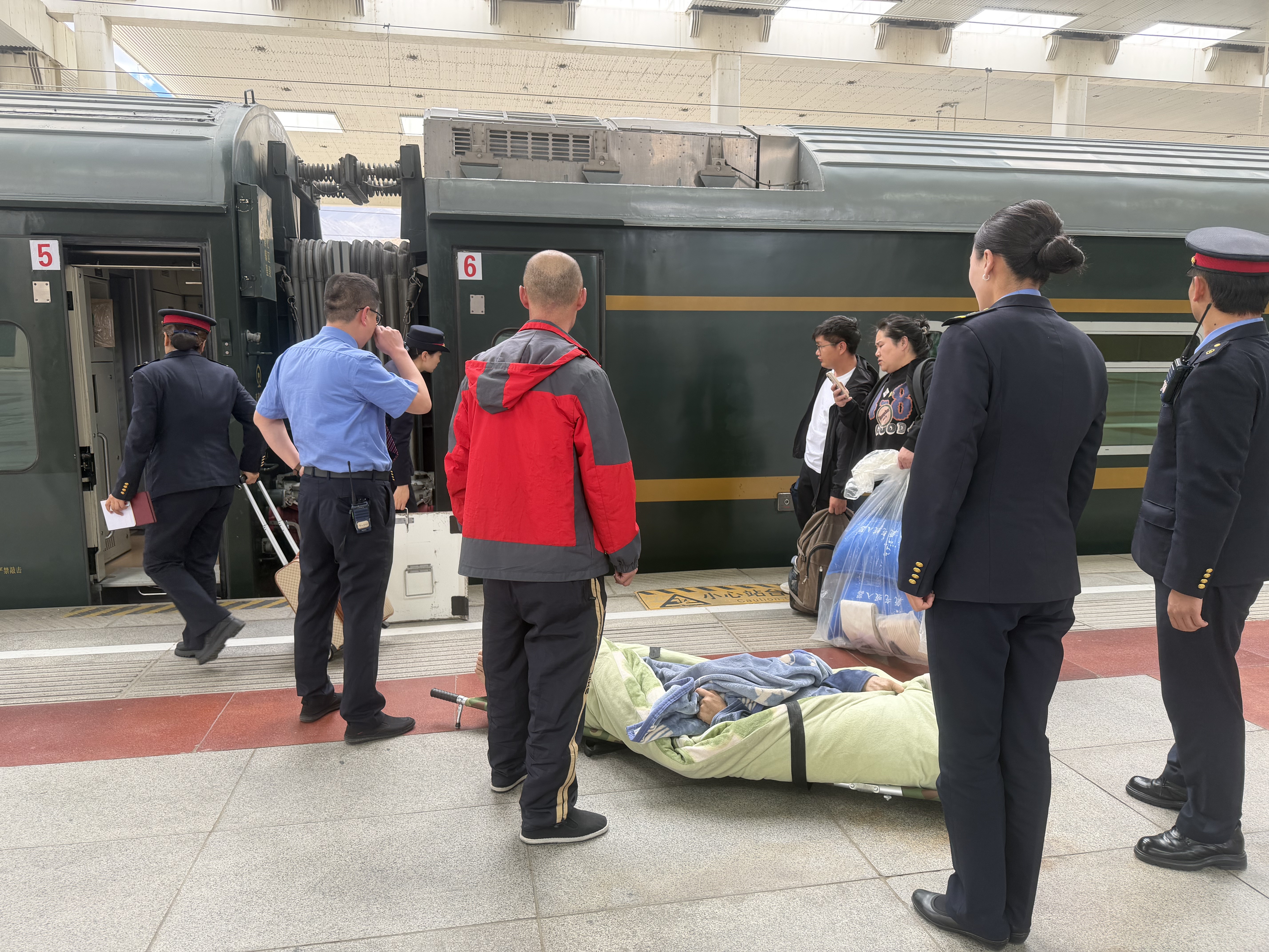 图为2026年6月9日，拉萨站站台上，客运员和列车员正将特殊旅客抬进卧铺车厢。记者 张宇 摄