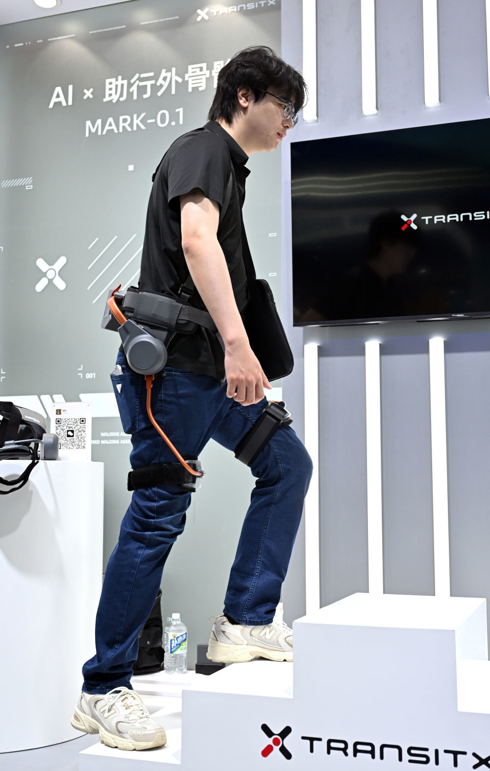 ↑ 4月14日，参观者在第六届消博会现场体验一款AI助行外骨骼。新华社记者 郭程 摄