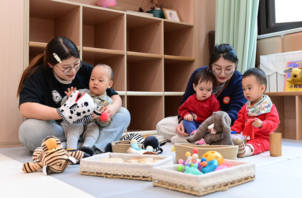 2025年3月19日，在鄂尔多斯市康巴什区神华康城社区“萌宝驿站”托育园，老师陪伴孩子做游戏。新华社发（王正 摄）