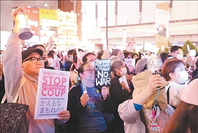 日前，日本民众在东京池袋站前的集会现场手持标语抗议。