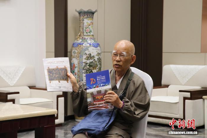 6月21日,小岛康誉在乌鲁木齐市接受中新社专访。图为小岛康誉展示其编写的与新疆相关的图书。 苟继鹏 摄