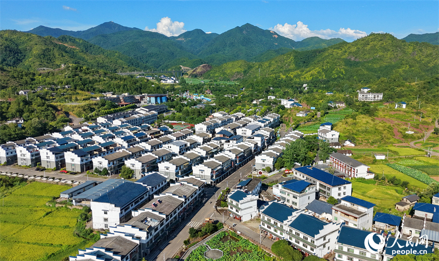 石城县琴江镇大畲村，一栋栋民居错落分布于青山田园间，与丹霞峰峦、青翠沃野相互映衬。人民网记者 朱海鹏摄