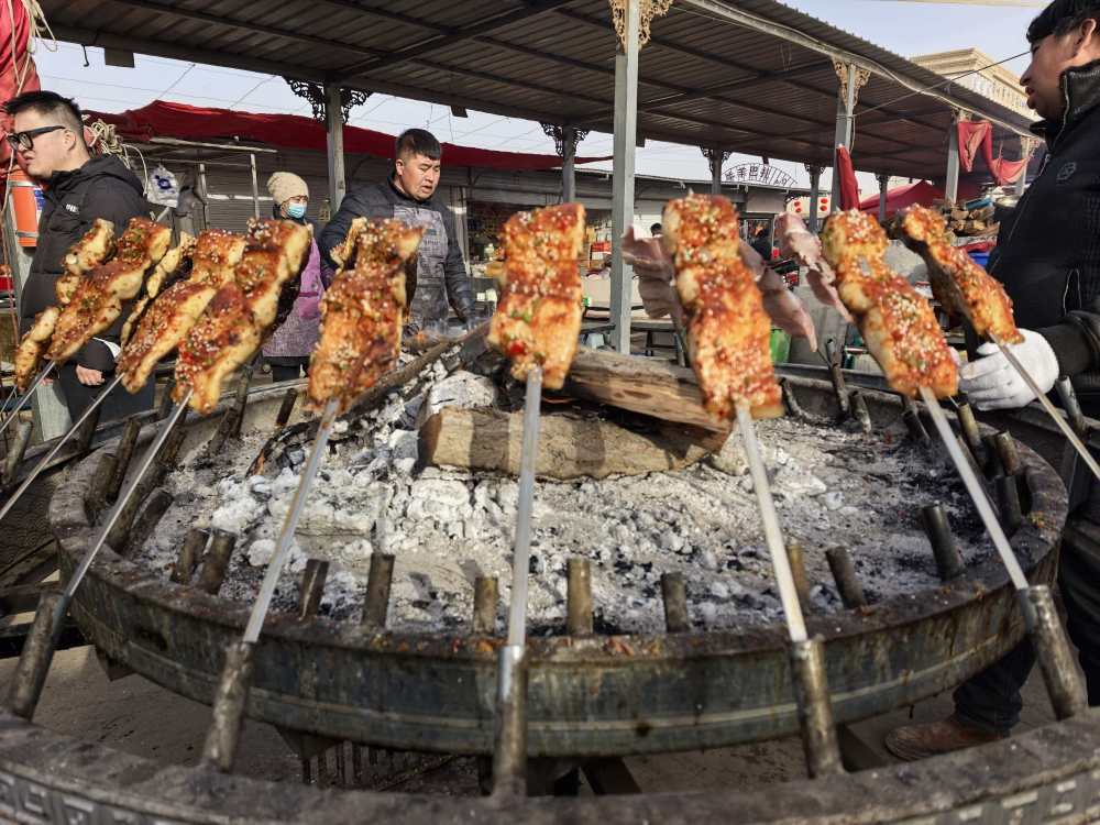 这是2月15日在喀什牛羊大巴扎上拍摄的售卖中的烤鱼。新华社记者 蔡国栋 摄