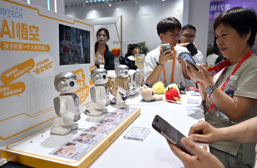 ↑ 4月14日，参观者在第六届消博会现场观看AI陪伴机器人。新华社记者 郭程 摄