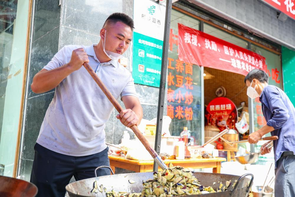 7月19日,志愿者为重庆彭水县山体崩塌救援现场的救援人员免费做午饭。