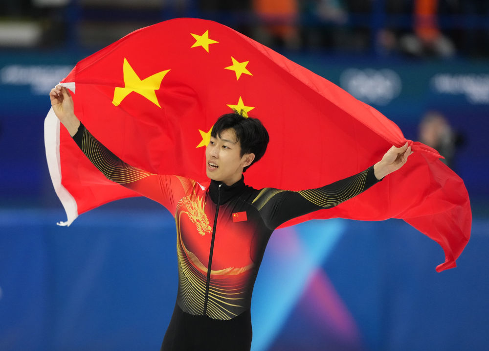 2月12日，亚军孙龙在短道速滑男子1000米A组决赛后身披国旗庆祝。新华社记者 薛宇舸 摄