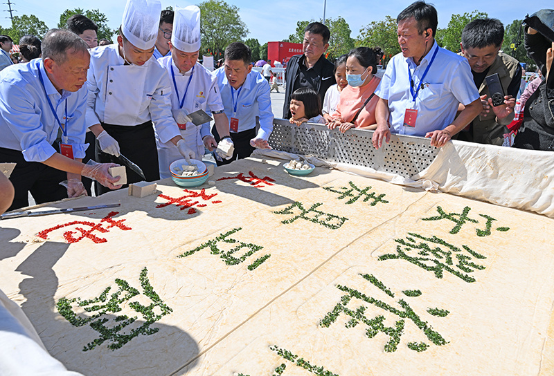 10月5日,游客在安徽省淮南市寿县古城千人豆腐宴现场品尝一块3000斤重的大豆腐。陈彬摄