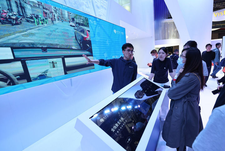 2025年4月25日,在第二十一届上海国际汽车工业展览会上,工作人员(左一)向观众介绍地平线辅助驾驶系统。新华社记者 方喆 摄