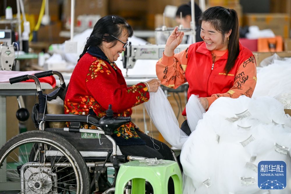 ↑ 5月16日，在贵州省开阳县紫兴街道蒋家寨易地扶贫搬迁安置点就业帮扶车间，社区志愿者和残疾人在交流。新华社发（袁福洪摄）