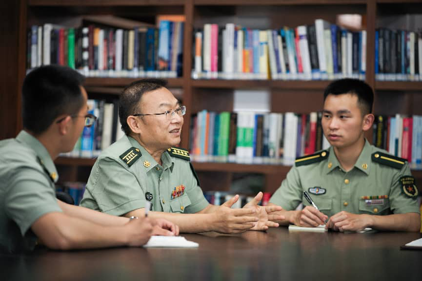 ↑国防科技大学计算机学院研究员王戟（中）在图书馆与学生讨论（2026年5月20日摄）。新华社发（范军威 摄）