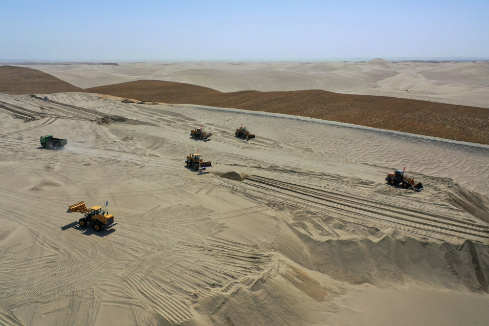 在新疆和田地区和田县三万亩群众防沙治沙区，大型机械在平整沙地（4月16日摄，无人机照片）。　 新华社记者 丁磊 摄