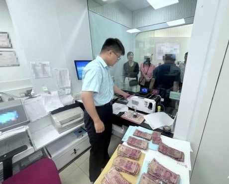 图为工作人员在柜台内为老年客户清点兑换残损人民币