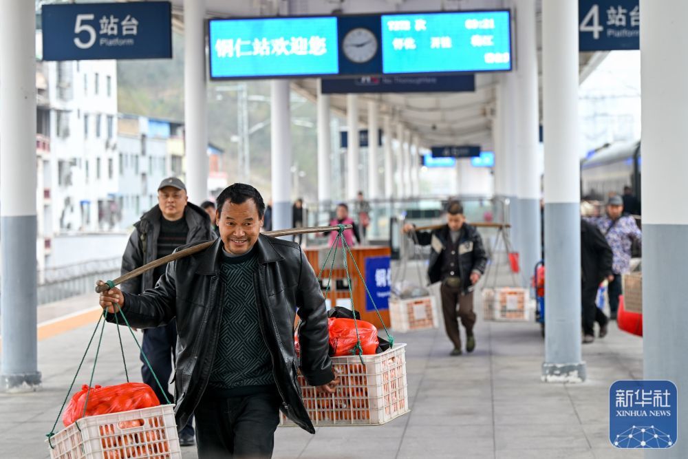 ↑ 2月12日,在贵州省铜仁市铜仁站,来自湖南的菜农挑着果蔬出站。新华社发(袁福洪 摄)
