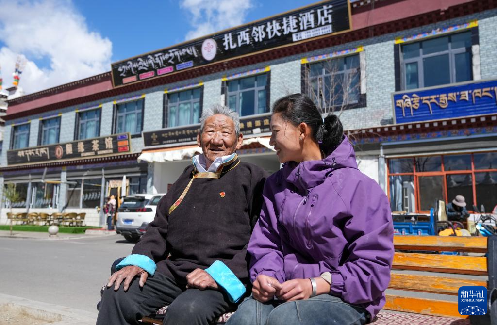 次仁桑珠(左)和孙女在自家酒店前的长凳上休息(3月25日摄)。