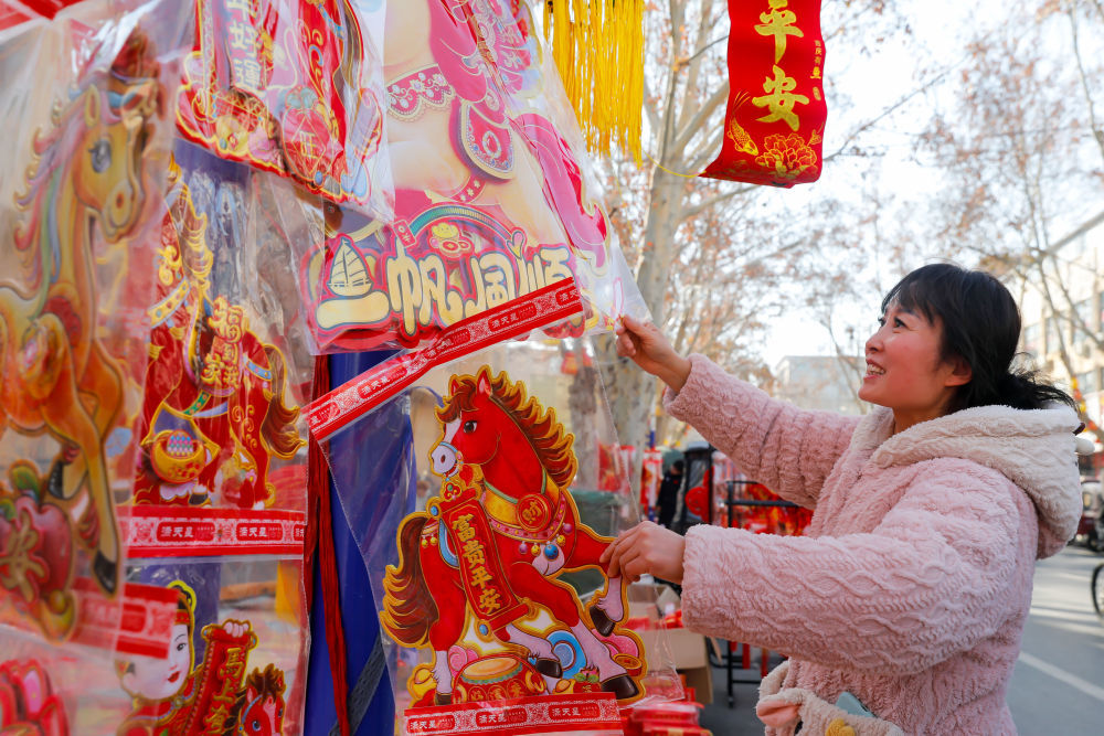 ↑ 2月14日，在河南省武陟县的一处年货市场，市民在选购新春饰品。新华社发（王琳锋 摄）