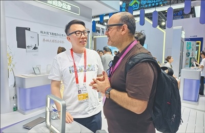 在消博会科大讯飞展台，参观者（右）体验人工智能眼镜的翻译功能。本报记者 褚 君摄