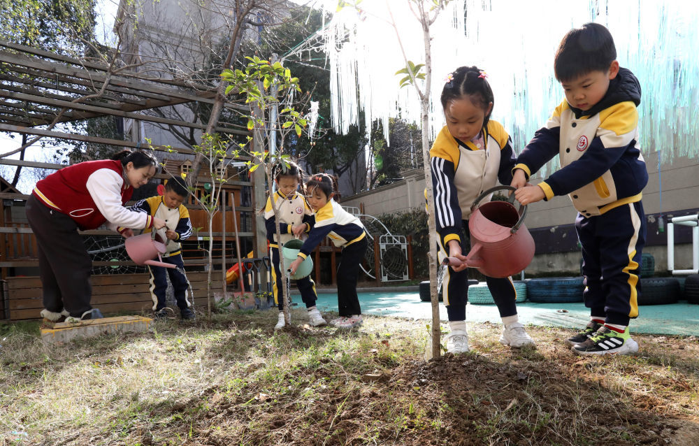 2026年3月10日，在江苏苏州高新区实验幼儿园，孩子们和老师一起给刚栽种的树苗浇水。新华社发（杭兴微摄）