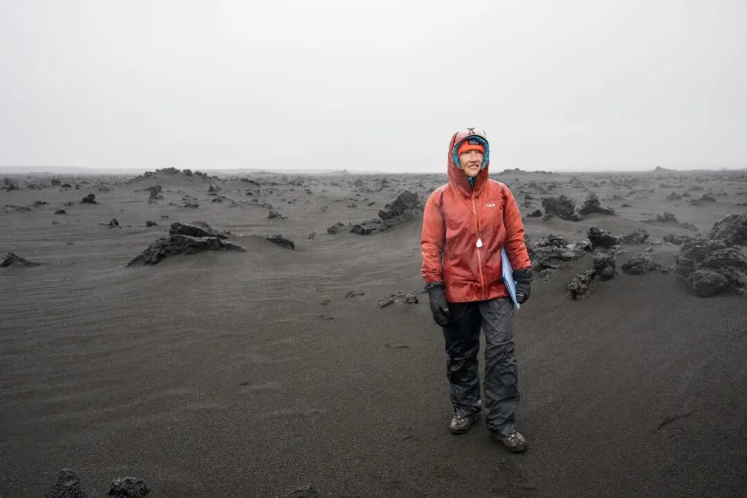 阿尔忒弥斯二号任务专家克里斯蒂娜·科赫(Christina Koch)在冰岛进行地质训练时,站在一片风势强劲的火山地貌中;该火山地形被用作月球地貌的类比环境。