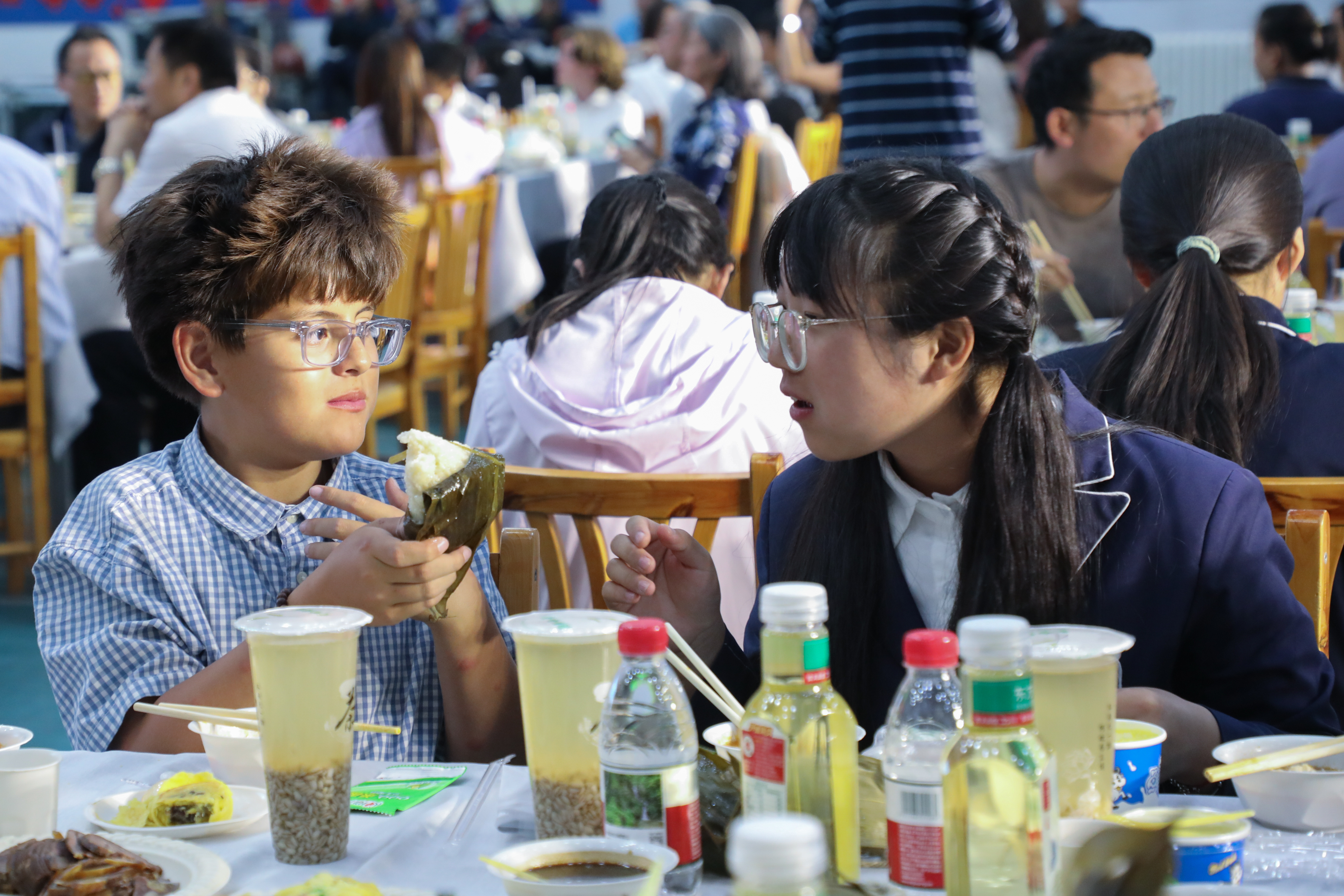2026年5月29日,美国犹他州文艺复兴学校41名师生代表到访青海省西宁市第二十一中学。图为西宁市第二十一中学学生向犹他州学生(左)介绍粽子的制作过程。 中新社记者 马铭言 摄