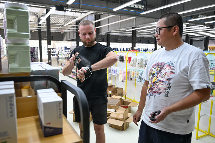 在新疆中哈霍尔果斯国际边境合作中心，来自哈萨克斯坦的主播瓦列里&middot;博洛托夫（左）在跨境电商孵化中心选品。（丁磊 摄）