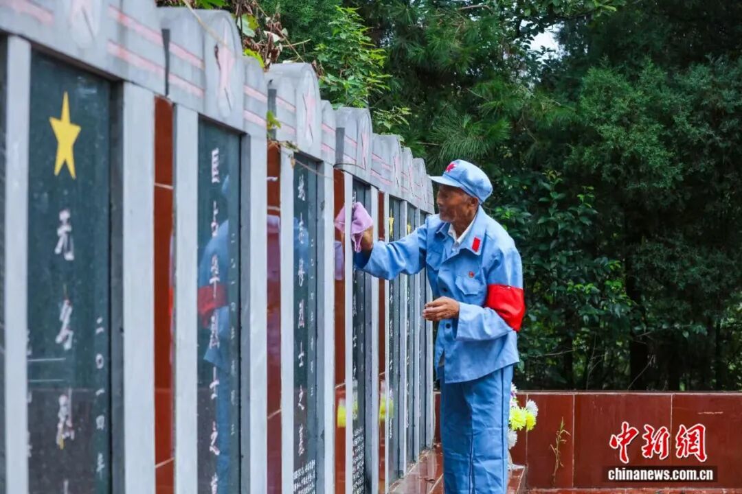 图为王茂贵老人在红军烈士墓前。光山县委宣传部供图