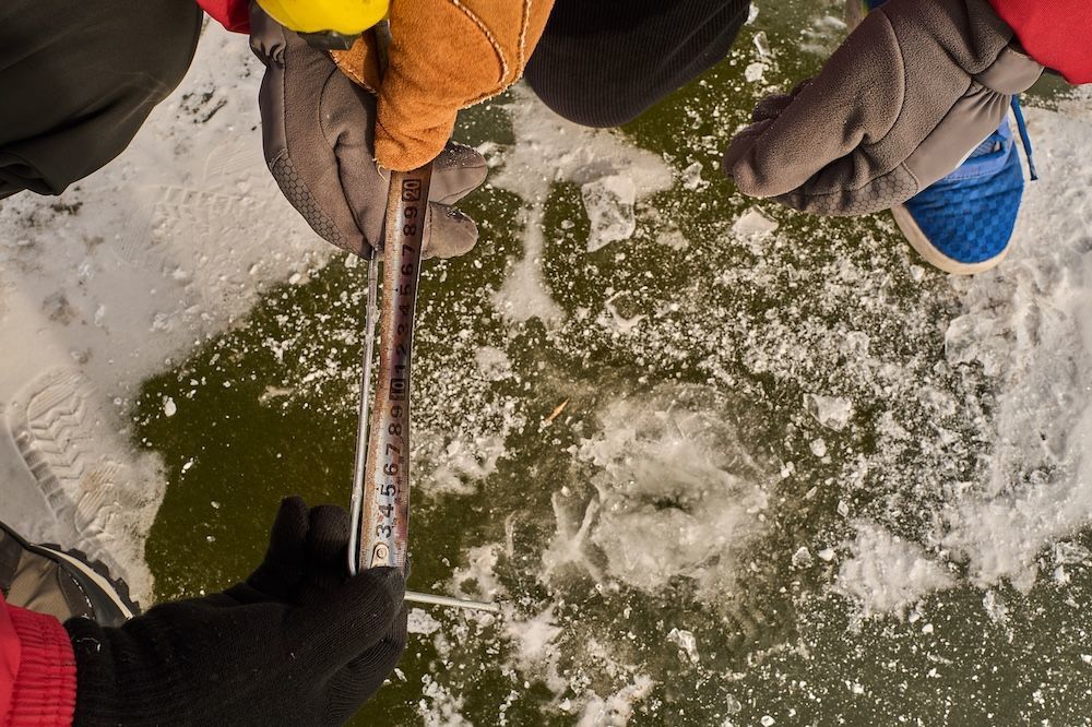 工友们跪在地上测量冰面的厚度。