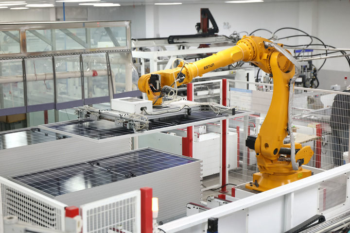 在江苏省淮安市洪泽区新源太阳能科技有限公司生产车间内,工业机器人在生产太阳能光伏组件(2025年12月17日摄)。新华社发(殷潮 摄)