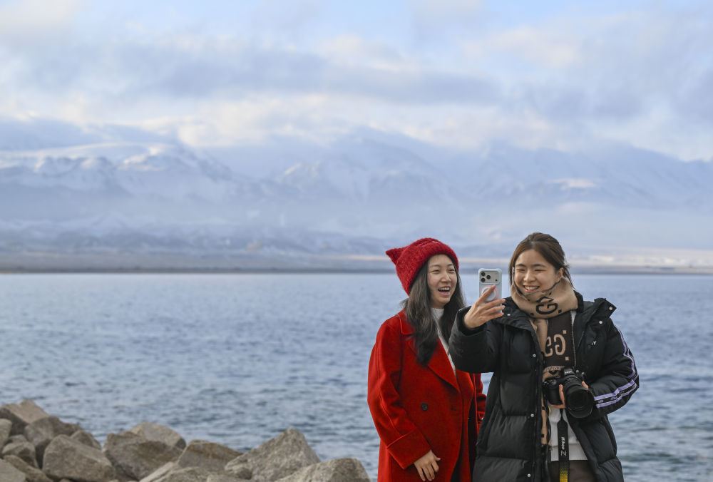 游客在赛里木湖边游玩留影。新华社记者 王菲 摄