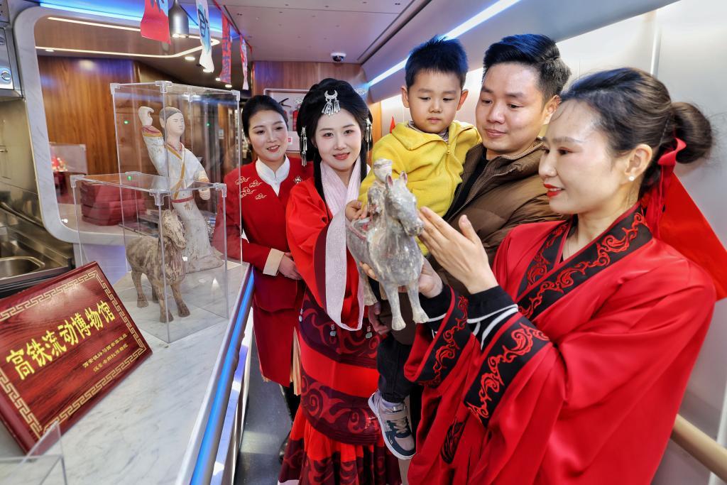 2月11日,西安北开往香港西九龙的G916次陕港高铁列车上,身着汉服的工作人员向旅客展示汉代马形文物复制品,并讲解相关历史文化。(国铁西安局集团公司供图)