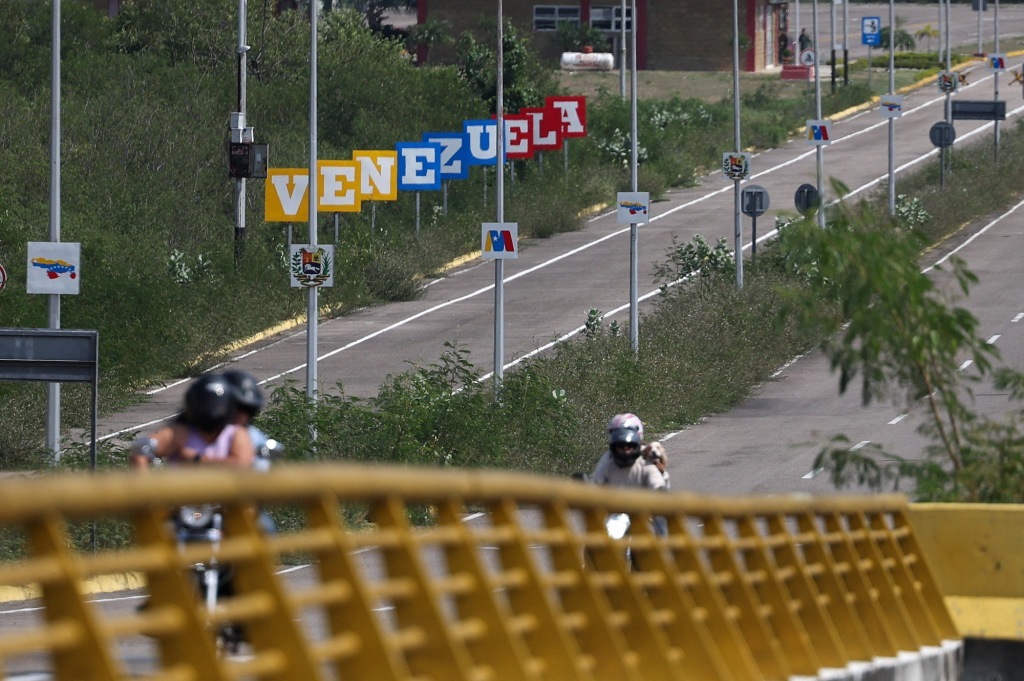 1月4日,人们骑摩托车通过连接委内瑞拉乌雷尼亚和哥伦比亚库库塔的廷迪塔斯边境大桥。新华社 图